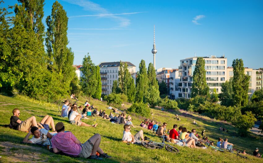 Many people relaxing in Mauerpark in Berlin on a sunny spring day, with the TV tower in the background