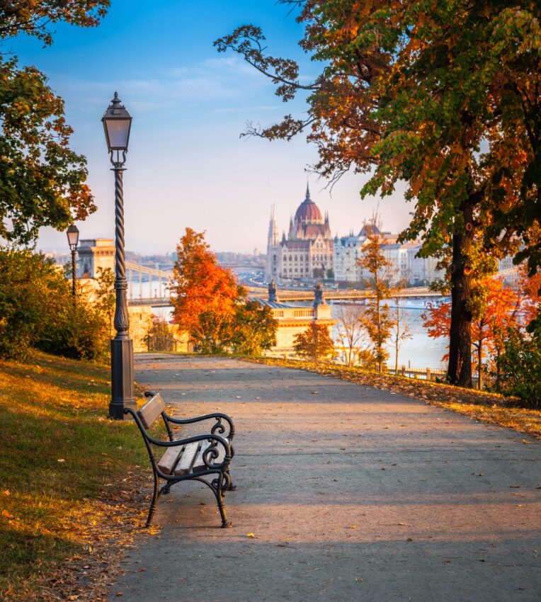 Romantic sunrise scene at Buda district with bench, lamp post, autumn foliage, Szechenyi Chain Bridge and Parliament at background