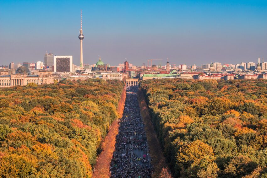 The Berlin skyline featuring the TV tower with trees in orange and green fall colors in the foreground