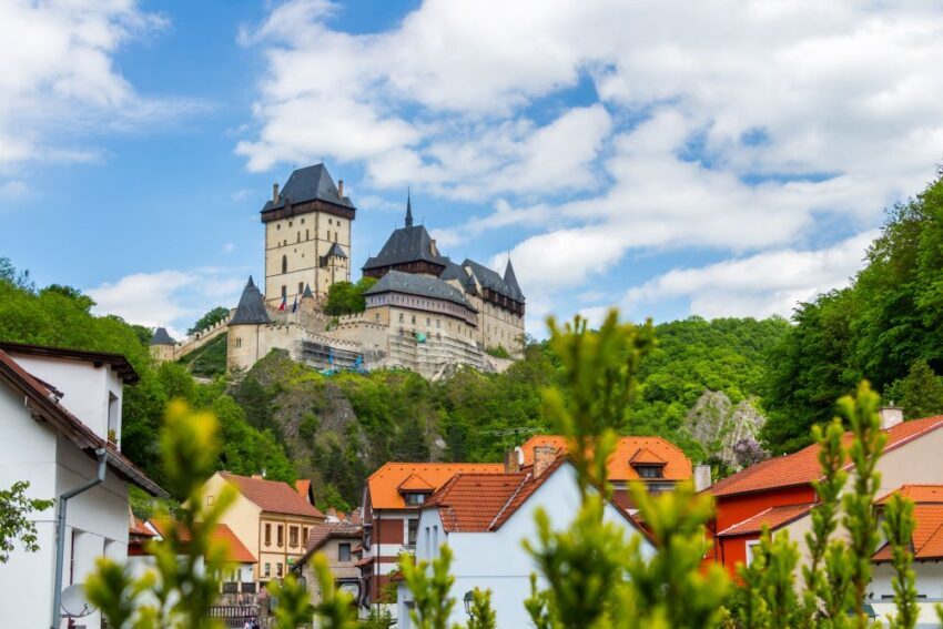 View of Karlstejn Castle in the Czech Republic, with the town in the foreground and a bright blue sky in he background