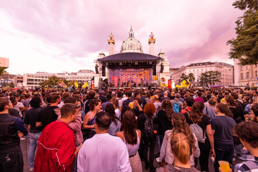 A crowd of festivalgoers looking on at the Popfet Wien mainstage in Vienna, Austria, on an overcast summer day